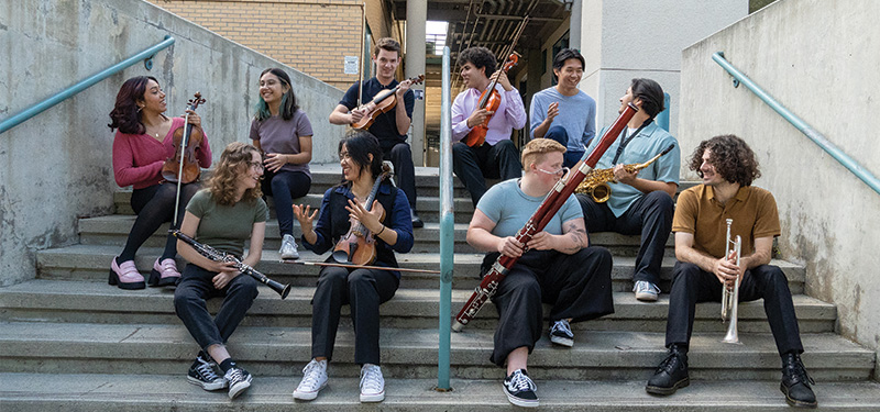 a group of students sitting on the stairs carrying instruments